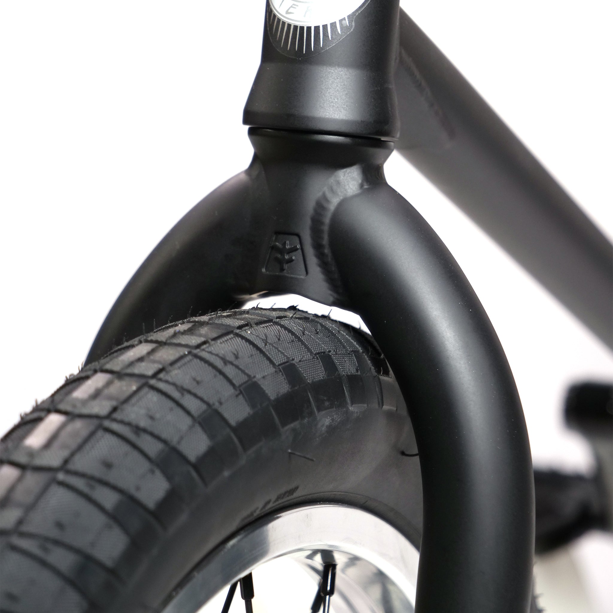 Close-up of a Fly Bikes Pajarito Custom 18 Inch BMX Bike's front tire and black frame, including the fork and part of the wheel rim.