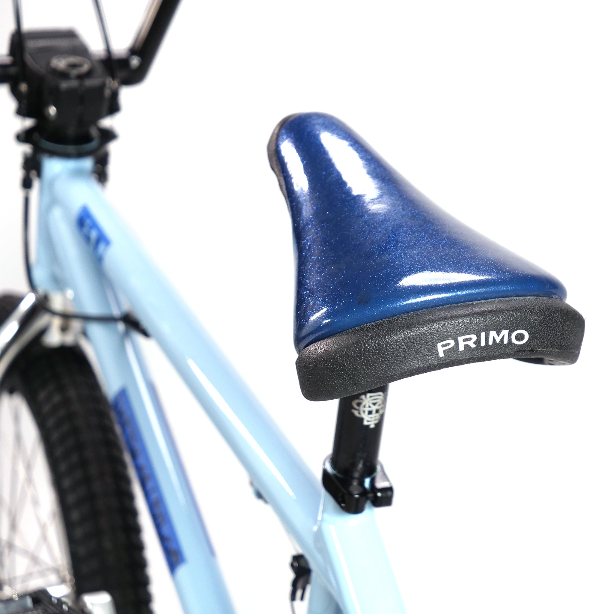 Close-up of a blue bicycle seat labeled "PRIMO," attached to a light blue 20-inch Hoffman TAJ Trend Adjacent Joy BMX freestyle frame.