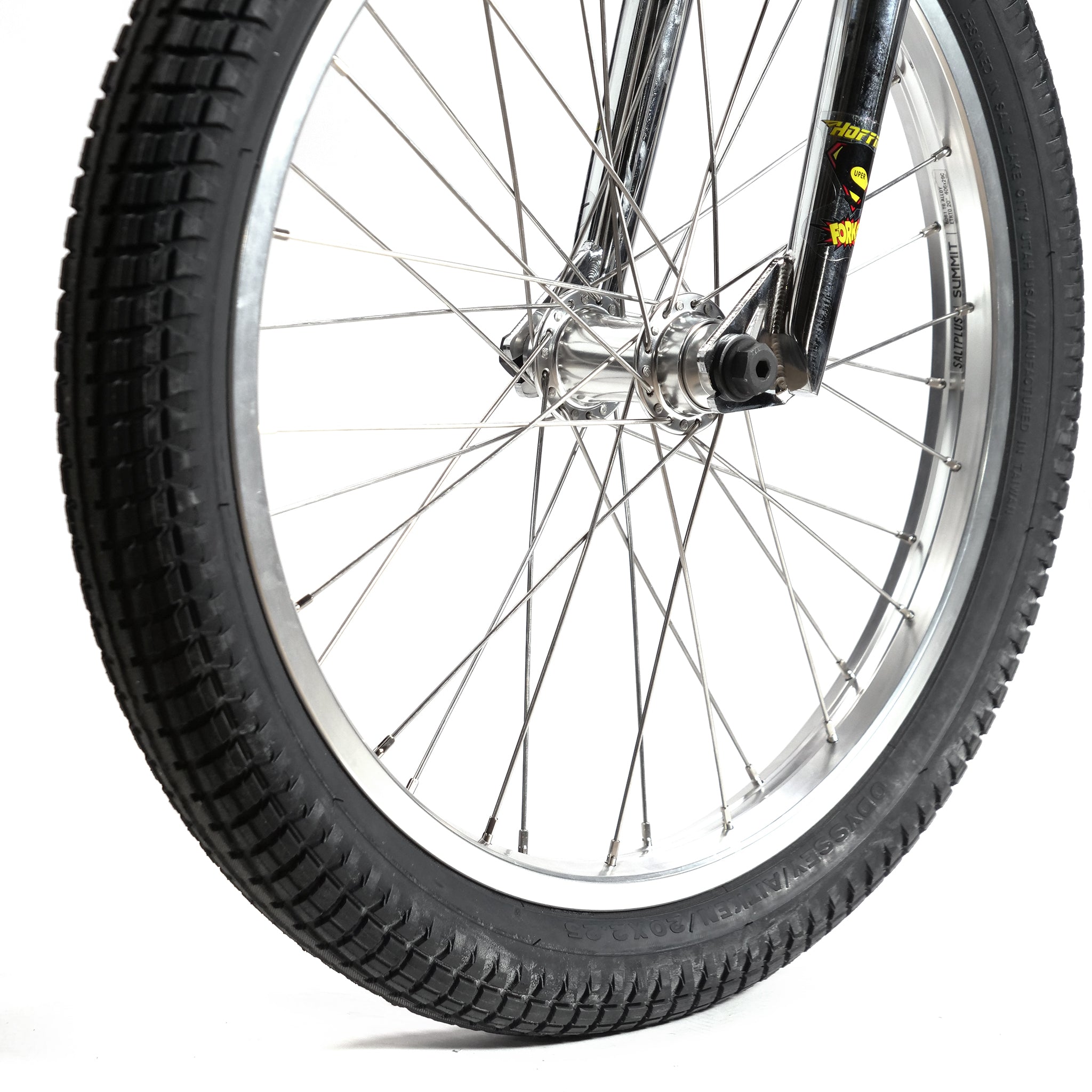 Close-up of the front wheel on the Hoffman TAJ Trend Adjacent Joy 20 Inch Custom Bike, featuring a black tire and silver spokes, seamlessly connected to a robust black fork.