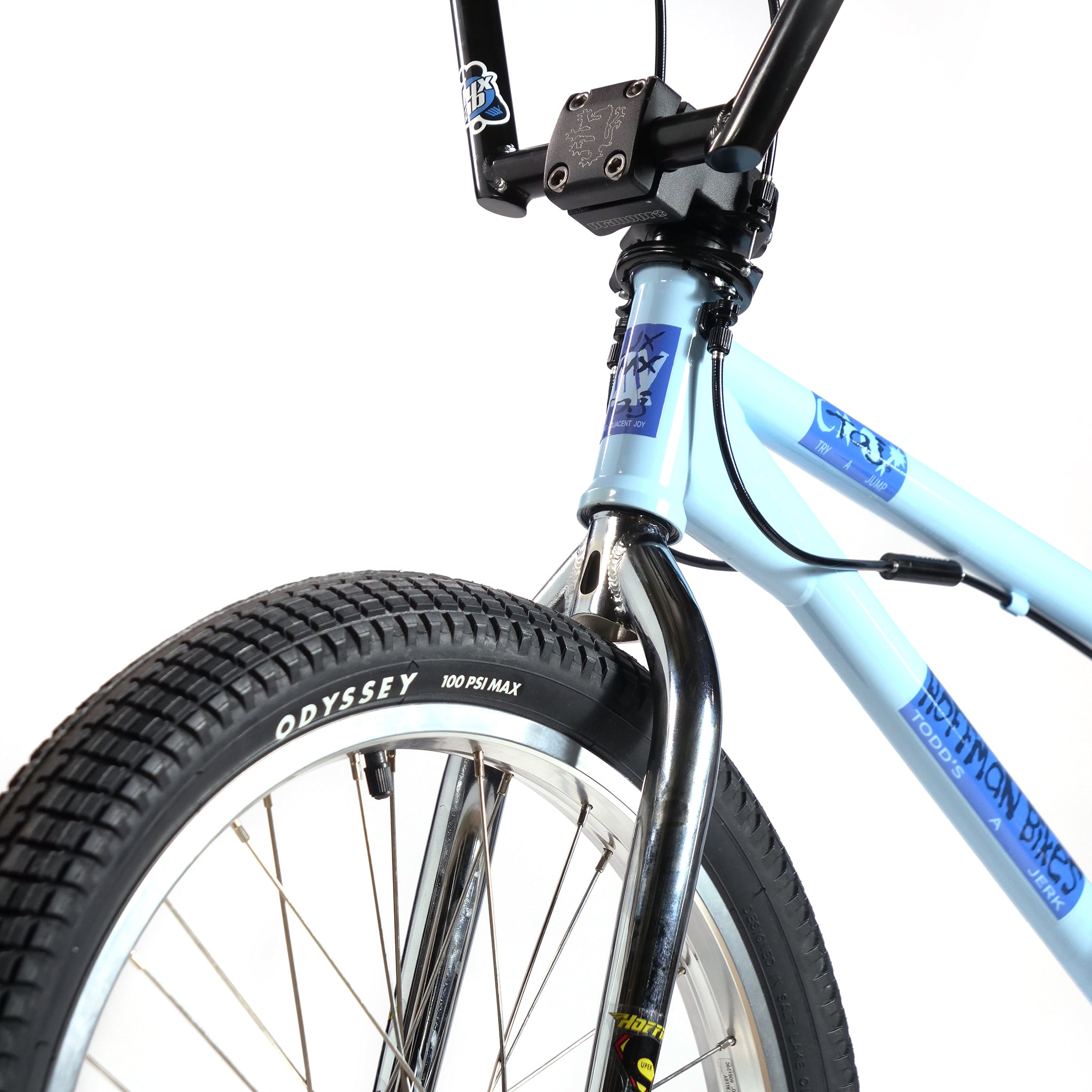 Close-up of the blue Hoffman TAJ Trend Adjacent Joy 20 Inch Custom Bike's front section, featuring the tire, fork, and handlebar stem set against a white background.