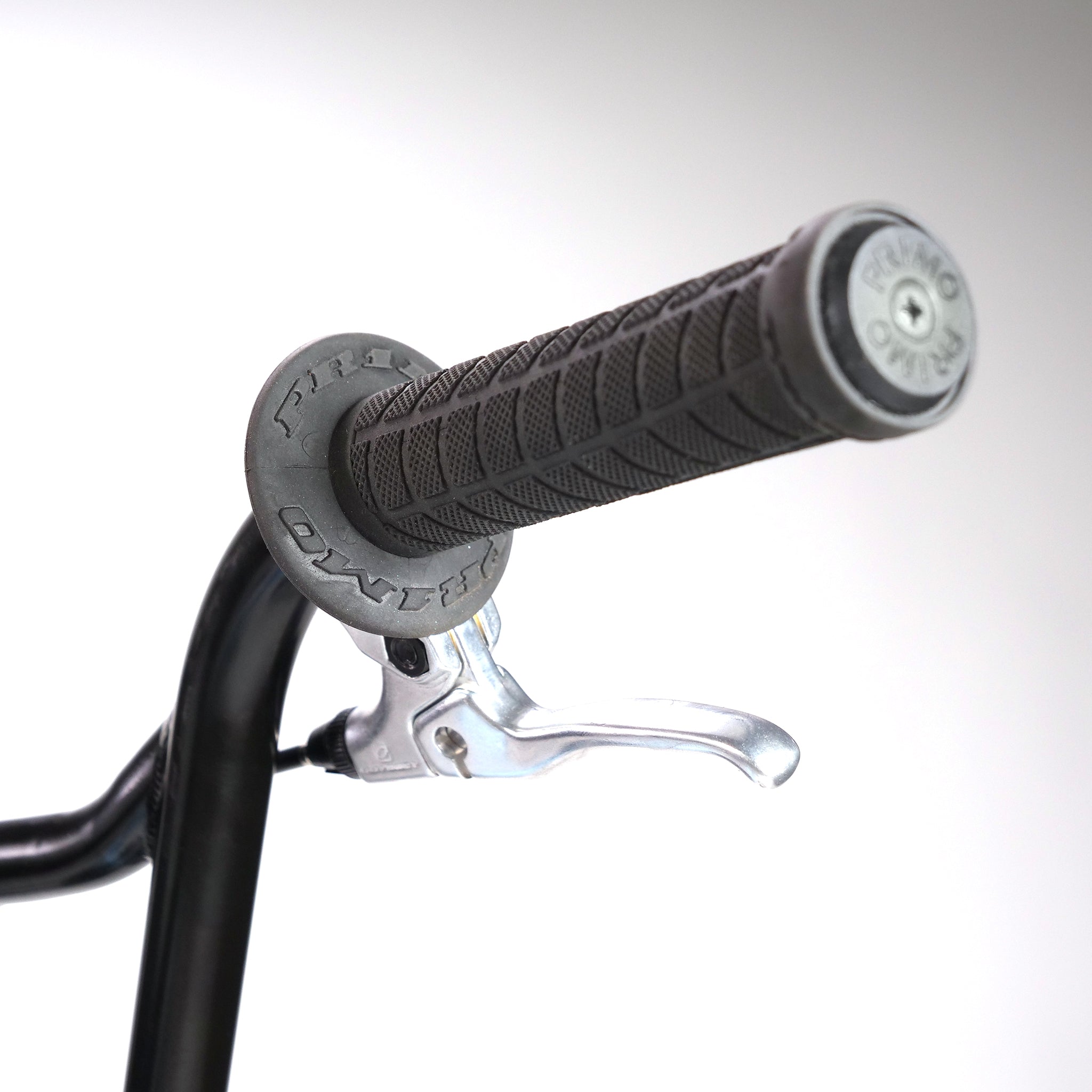 Close-up of a black bicycle handlebar with a textured grip and silver brake lever, reminiscent of the sleek designs in the Hoffman TAJ Trend Adjacent Joy 20 Inch Custom Bike.