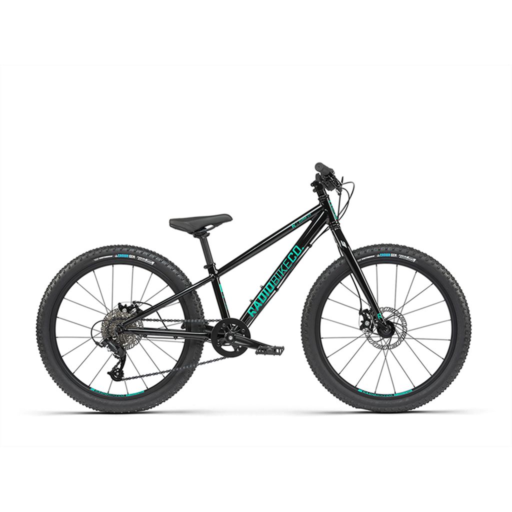 The Radio 24 Inch Zuma Bike is a black mountain bike with teal accents, featuring large tires, a front suspension fork, and disc brakes. Designed for rugged terrain, it boasts a lightweight alloy frame perfect for adventurous rides.