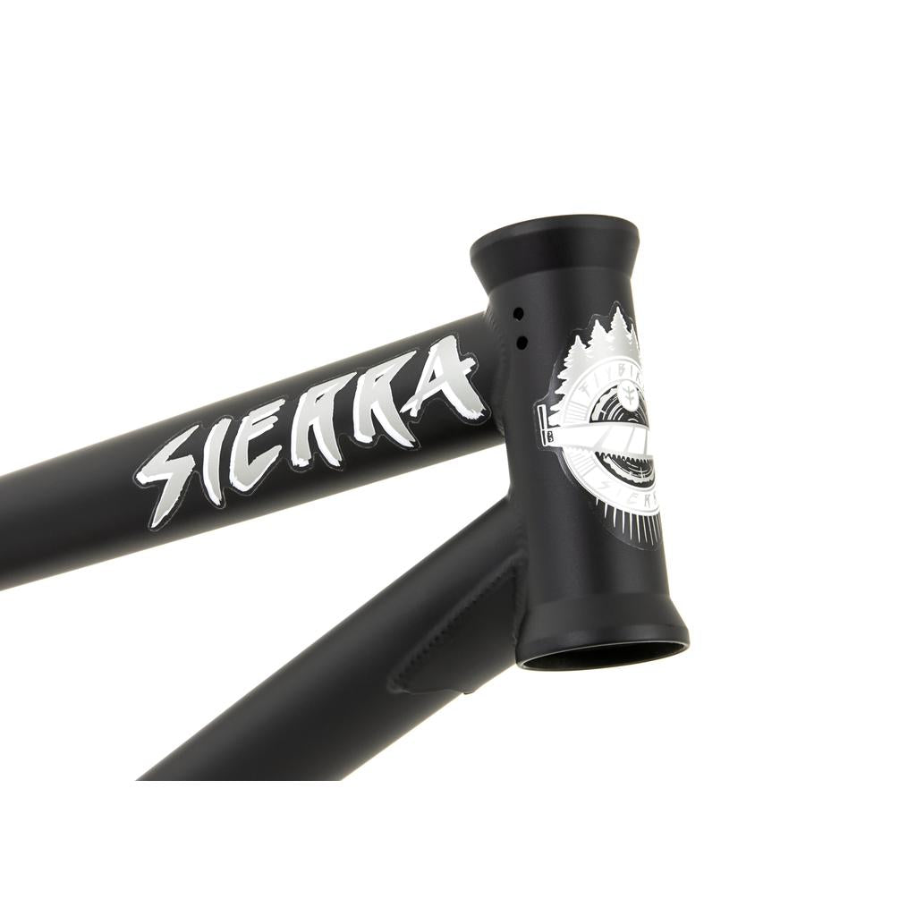 Close-up of the Fly Bikes Sierra Frame made from 4130 CrMo, featuring "Sierra" in white on its sleek black surface. Near the joint is an emblem with a mountain and gear design that adds rugged elegance.