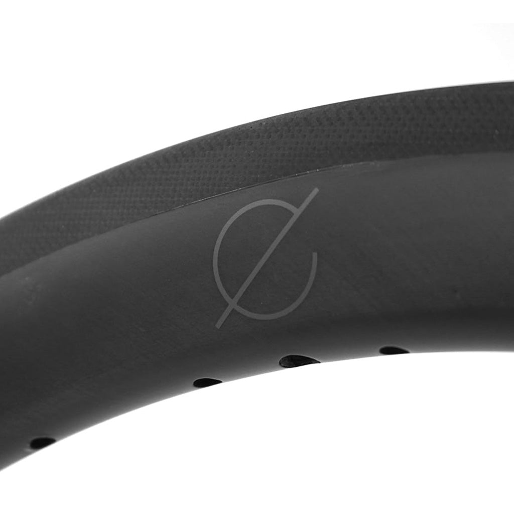 A close up image of a black Spectre Carbon Fibre 507x30mm Rim bicycle tire featuring carbon fibre construction.