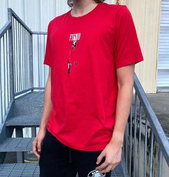 Someone wearing the Fiend Tony Montana Shirt, which features a striking graphic design crafted with discharge printing, stands confidently on a metal staircase.