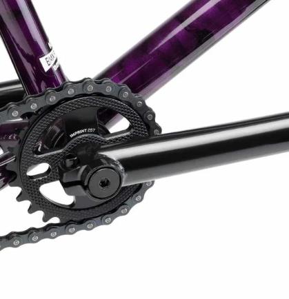 Close-up of the Kink Imprint Sprocket's black crankset and chainring on a purple frame, highlighting intricate gear details crafted from durable 7075-T6 aluminum.