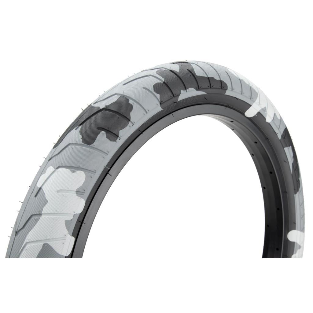 The Kink Sever Tyre boasts a bold white, gray, and black camo design on a white background. Ideal for street and park riding, it offers excellent grip to elevate your experience.