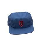 The Terrible One Patch Camp Cap is a five-panel blue baseball cap made from cotton twill and features an embroidered badge logo with a red "T" emblem on the front.