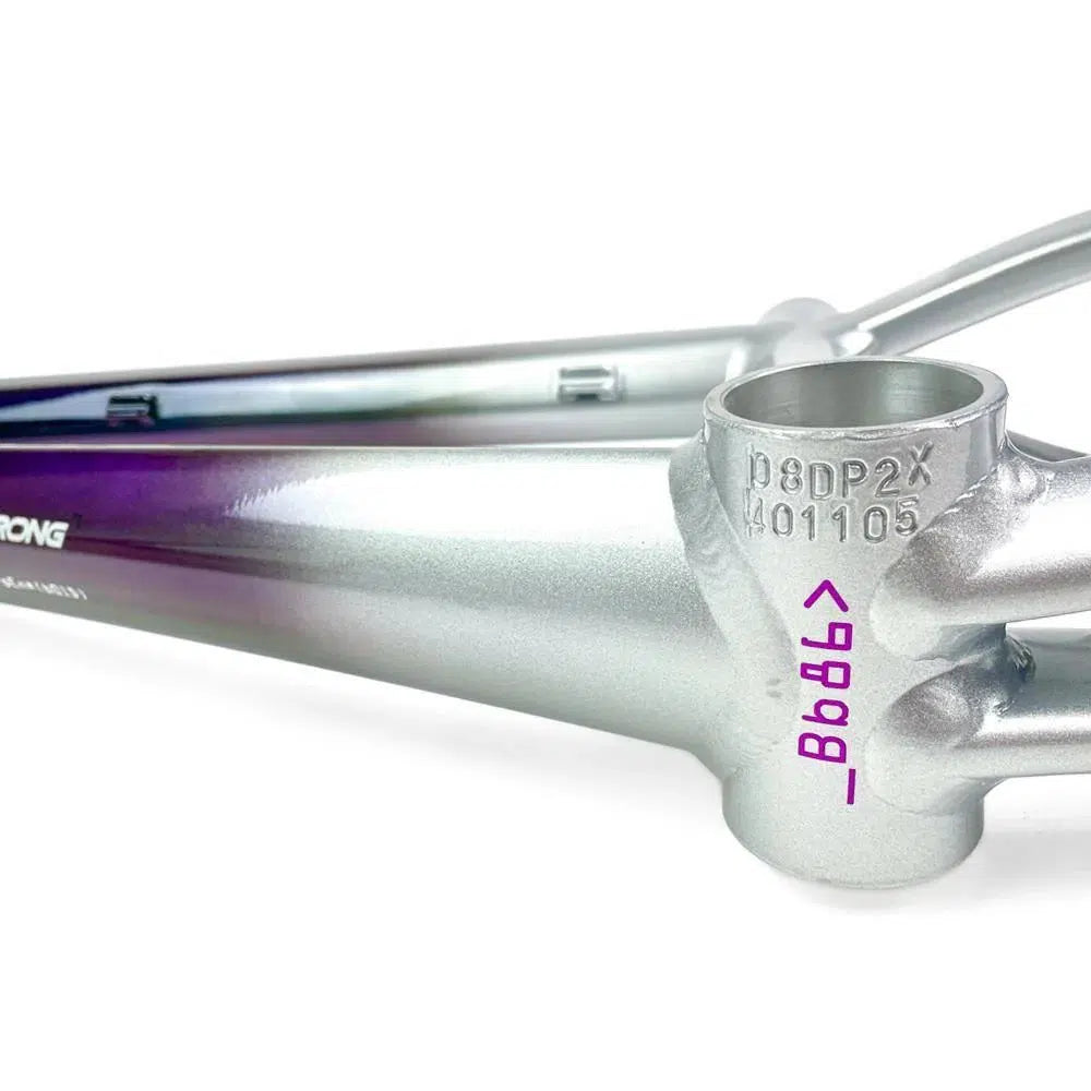 Close-up of a metallic, aluminium Staystrong V5 Disc Pro XXXL Frame with the bottom bracket shell showing engraved serial numbers. The 6061 alloy tubing features a stunning gradient finish transitioning from silver to purple.