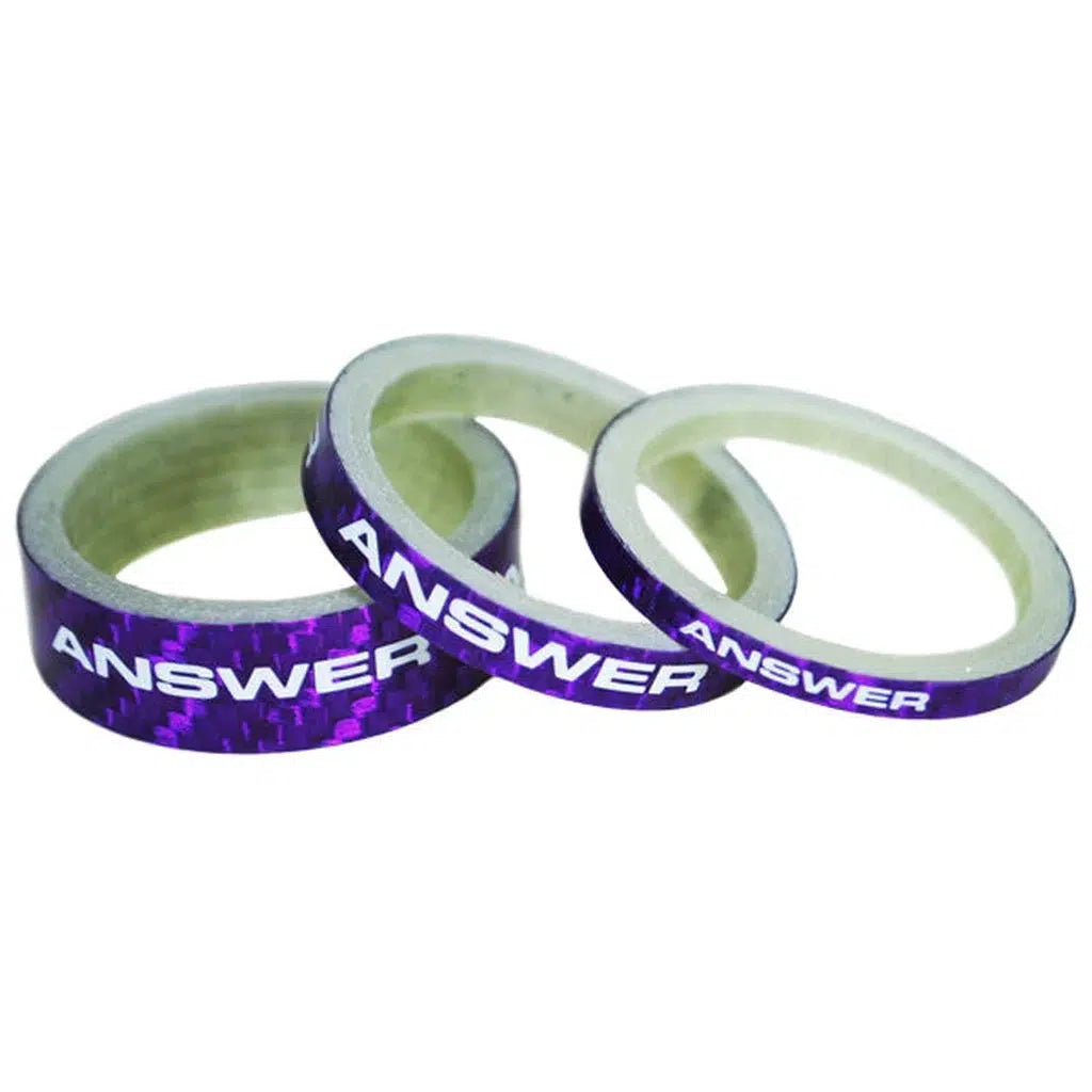 The Answer Mini 1in Carbon Headset Spacer set, consisting of three purple spacers, is designed for 1-inch forks and features the word "ANSWER" printed in white, providing a stylish option to adjust your stack height.