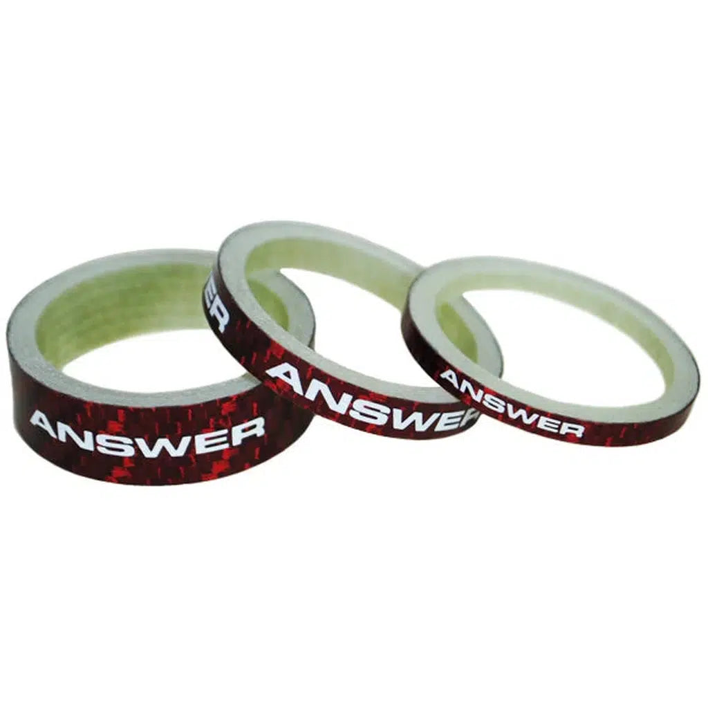 A set of Answer Mini 1in Carbon Headset Spacers, featuring three spacers, perfectly complements three rolls of red tape with "ANSWER" printed in white.