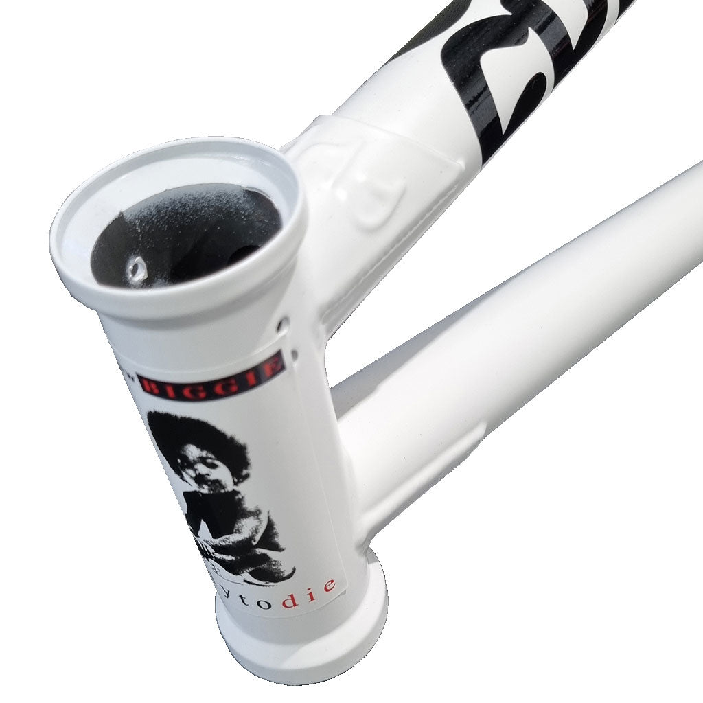 Close-up image of the head tube of a white Cult Biggie Frame (Devon Smilie Signature), featuring a sticker of a person and text, emphasizing its street geometry.