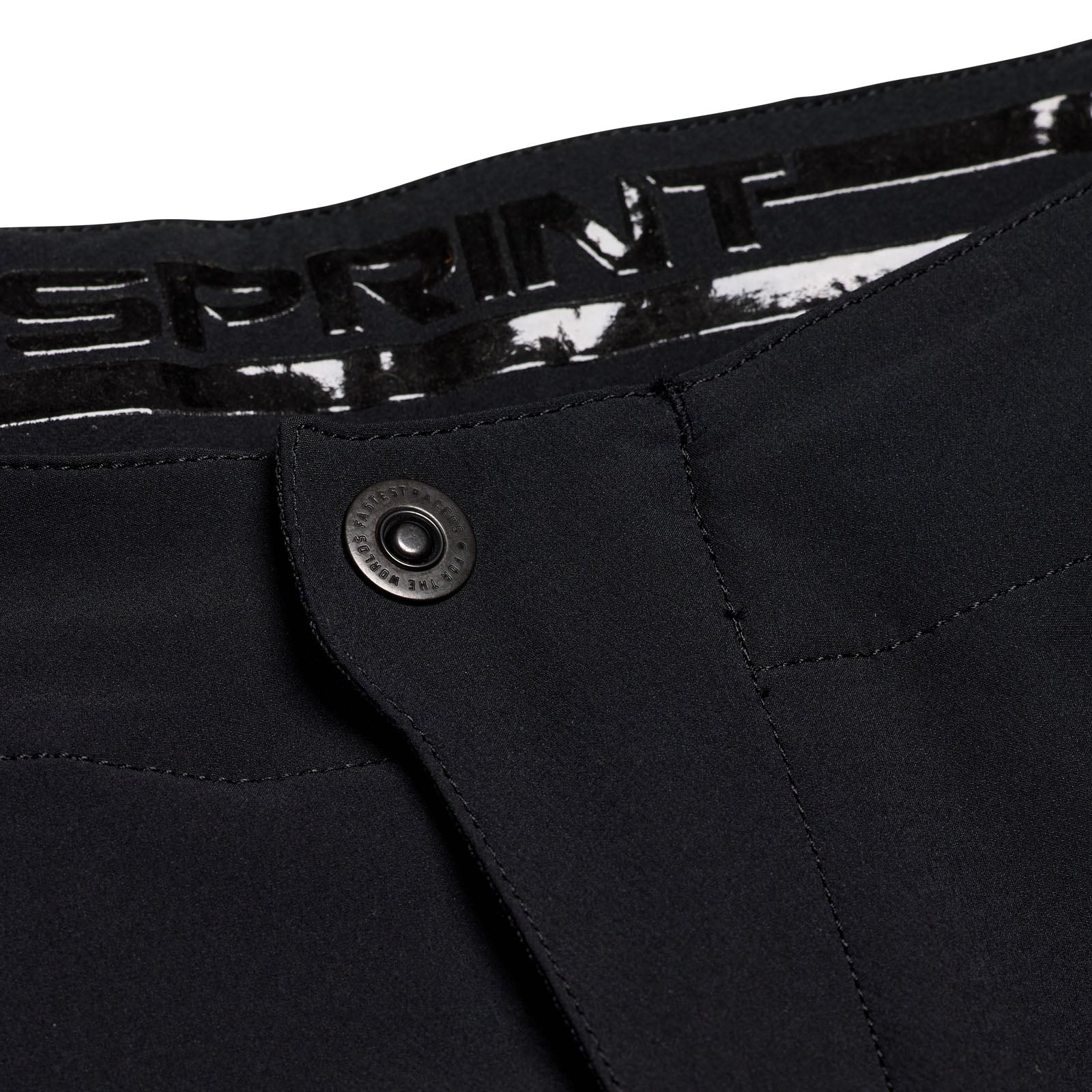 Close-up of the TLD 25.1 Sprint Pant in Mono Black by Troy Lee, featuring a button closure. The waistband boldly showcases "SPRINT," highlighting its race pant heritage.