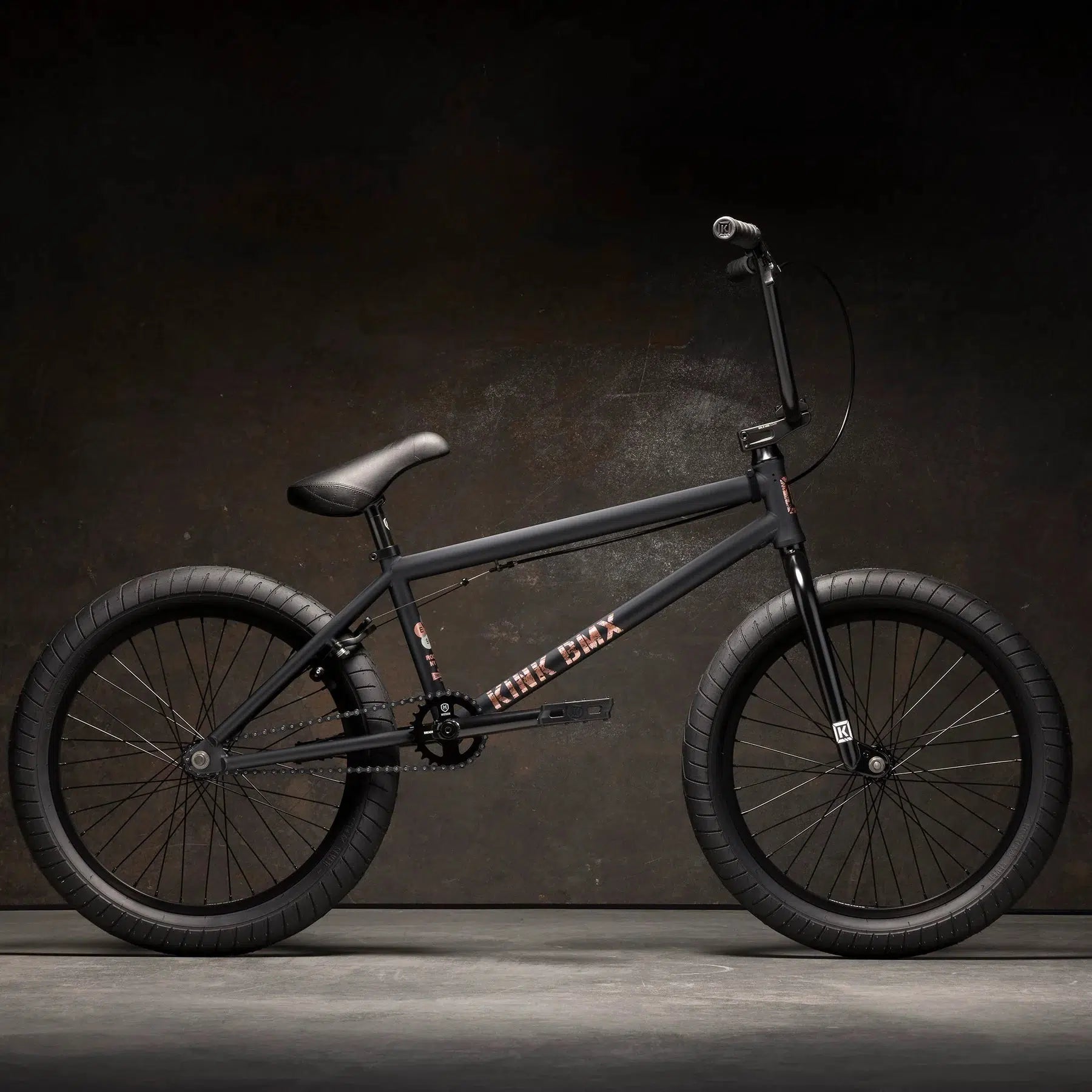 The Kink Gap XL 20 Inch Bike, featuring modern geometry and a thick-tired design, boasts a sturdy 4130 Chromoly frame. It's elegantly displayed against a dark background, highlighting its robust build.