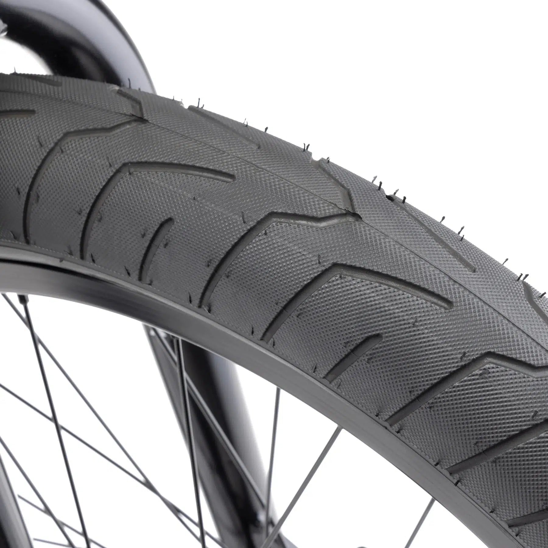 Close-up of a bicycle tire featuring a textured tread pattern mounted on a spoked wheel, highlighting the modern geometry and robust design of the Kink Gap XL 20 Inch Bike frame.