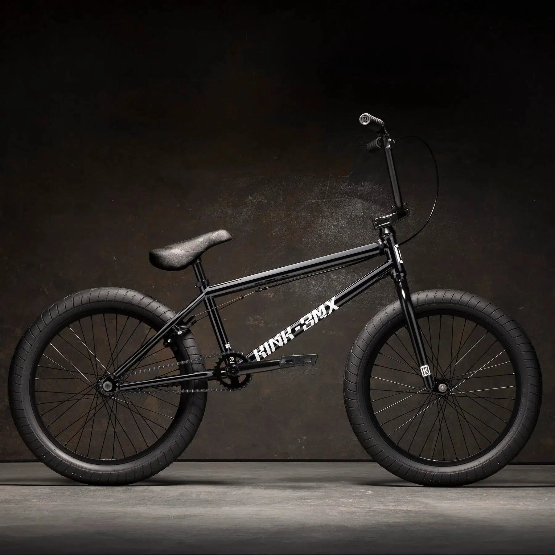 The Kink Launch 20 Inch Bike, featuring a robust black frame and knobby tires along with a sealed integrated headset, stands boldly against a dark background.