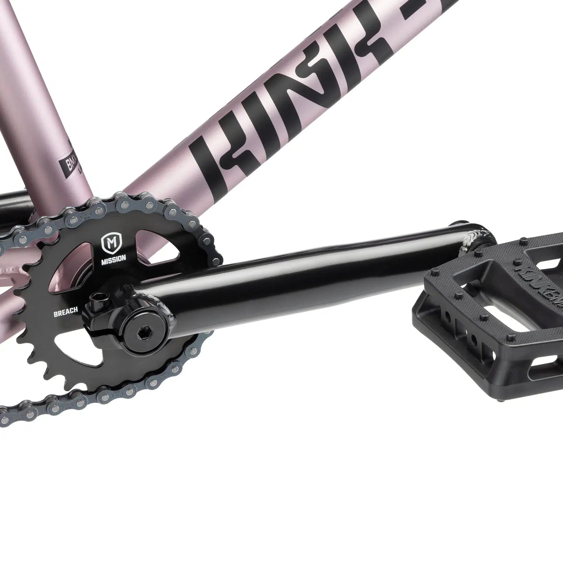 Close-up of the drivetrain on the Kink Launch 20 Inch Bike, showcasing a black crank arm, chainring, and pedal, all seamlessly integrated into its vibrant pink frame.