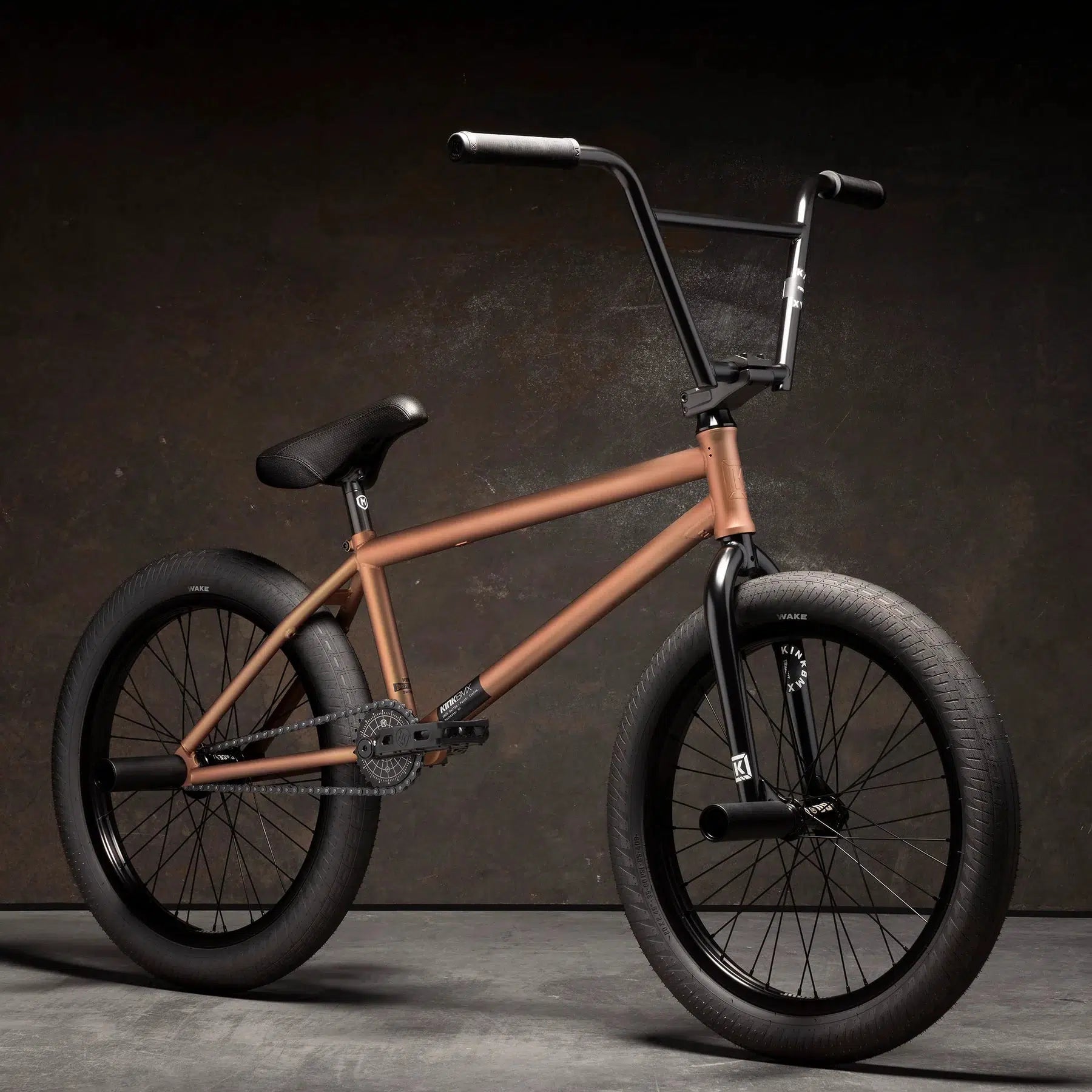 The Kink Switch 20 Inch Bike, in a stylish matte bronze finish, showcases a robust Chromoly frame and freecoaster. It features thick black tires, a black seat, and handlebars set against a dark background.