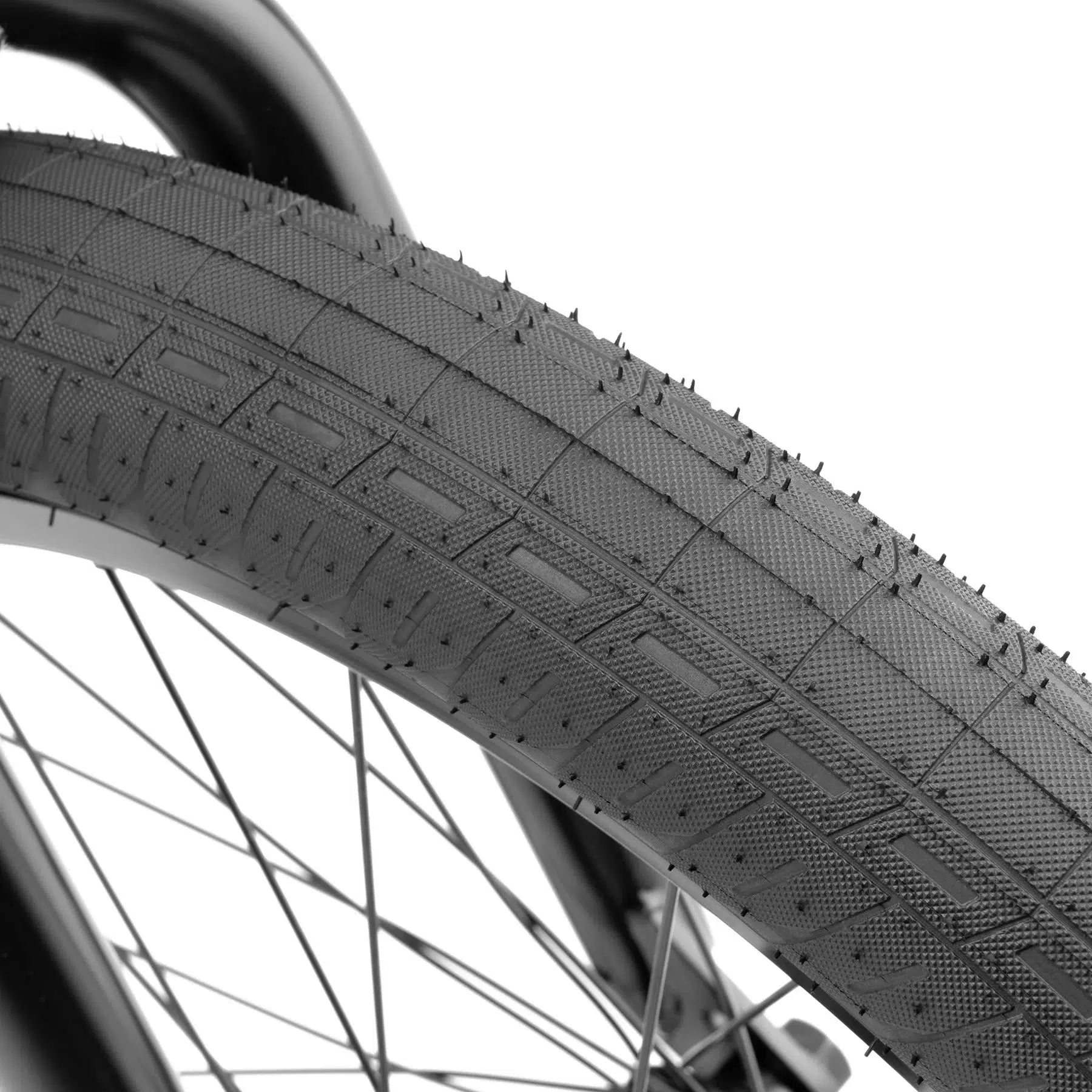 Close-up of a tire from the Kink Switch 20 Inch Bike, featuring a textured tread pattern, mounted on a spoked wheel.