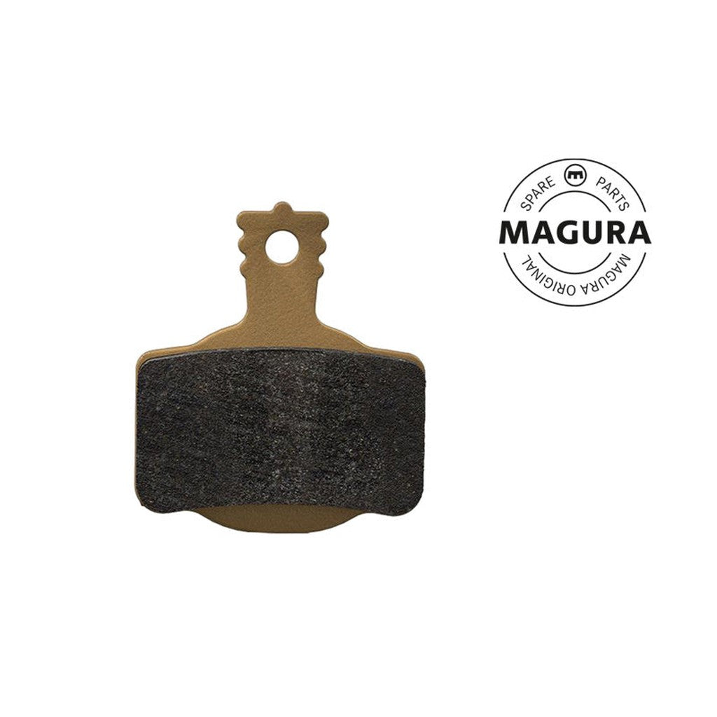 A Magura 7 Series MT Disc Brake Pad in brown and black, featuring a round top hole and branded with "MAGURA" in the top right corner, displaying the “SPARE PARTS MAGURA ORIGINAL” circular logo. These brake pads are designed with a performance compound for enhanced durability.