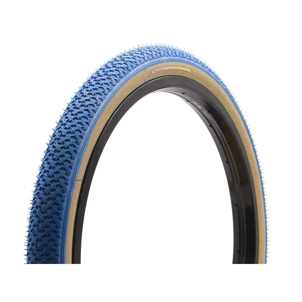 A blue bicycle tire with an original tread pattern, black sidewalls, and a thin tan line near the edge. The tire is upright, shown in a three-quarter view, and designed for 85 PSI performance. Perfectly suited for Panaracer Freestyle HP Tyre enthusiasts seeking quality and style.