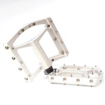 A pair of Stay Strong FORCE Pro Platform Pedals with multiple grip pins on a white background. One pedal is standing upright while the other lies flat.