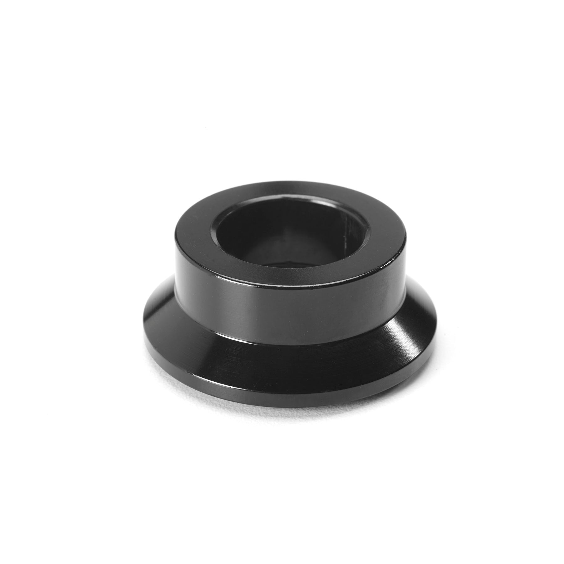 A black, cylindrical metal object resembling the Kink Yukon Cassette NSD Cone with a wide base and hollow center rests on a white background, possibly serving as a non-drive side replacement cone.