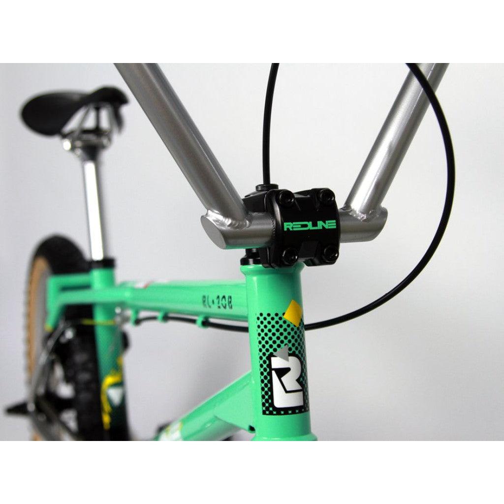 Close-up of a mint green frame with black handlebars and seat, featuring the iconic "Redline" logo on the front, showcasing a classic BMX design reminiscent of the Redline RL20B Retro 20 Inch Bike era.