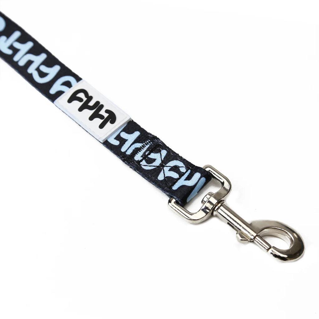 A close-up of the Cult Dog Leash in black and blue, similar to a heavy-duty dog leash, showcases abstract symbols in a repeating pattern with a metal clip at the end.