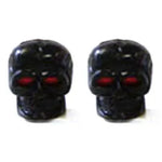 Two black Skull Valve Caps with piercing red eyes form an eerie pair, side by side on a white background.