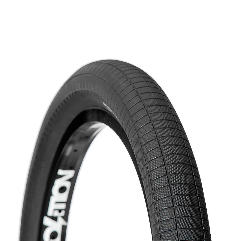 Close-up of a durable black bicycle tire with a textured tread pattern, partially mounted on a wheel rim. This superior design is akin to the Hammerhead - Street (S) Folding Tire, ensuring both strength and lightweight performance for avid cyclists.