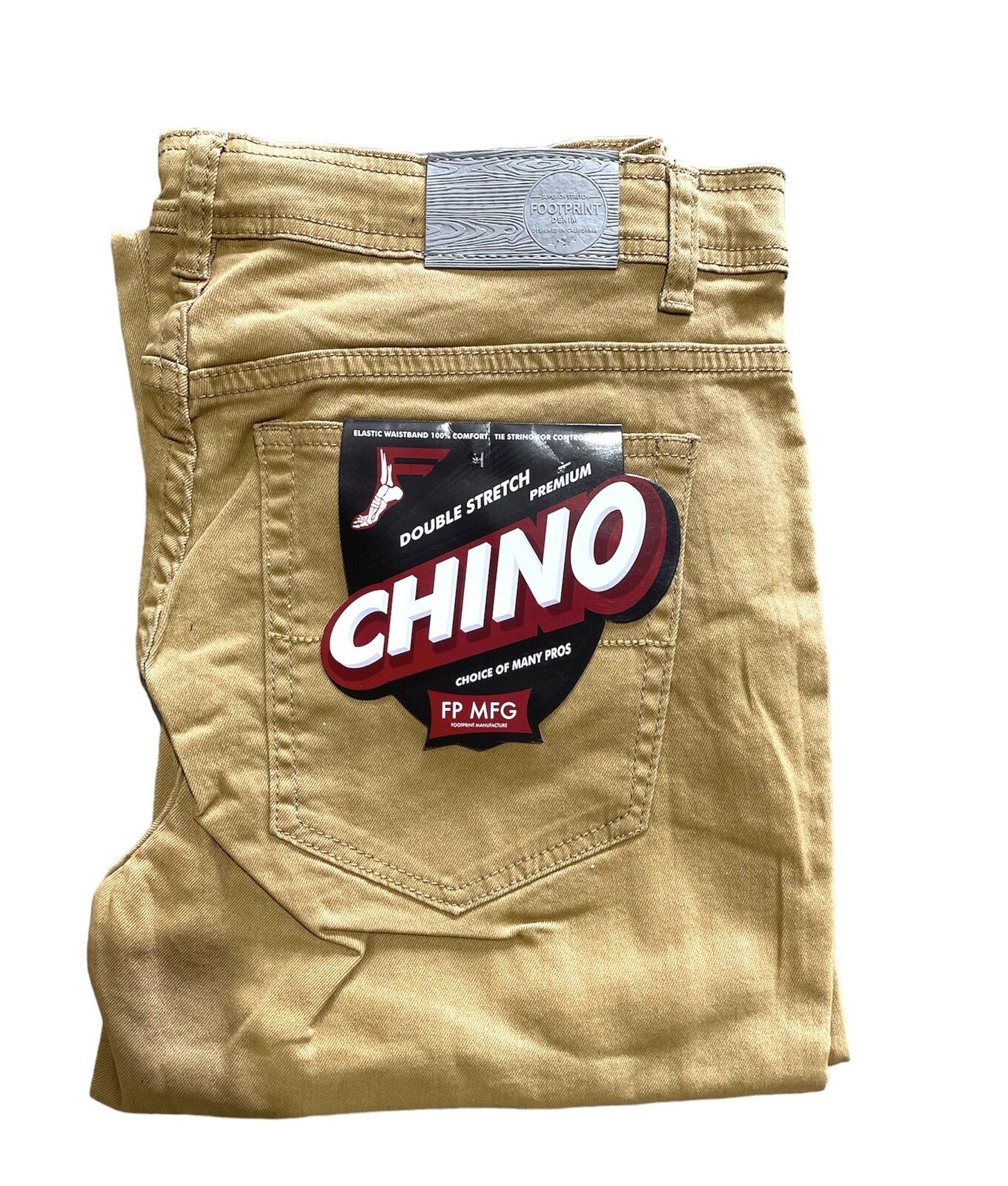 Folded pair of beige chino pants with a label on the back pocket that reads "FP Pants Relaxed Fit Chino Tan" and "FP MFG." These relaxed fitting chino pants offer both comfort and style.