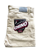 A pair of beige chino pants folded neatly, with a label on the back pocket that reads "Double Stretch Premium Chino, FP MFG." These FP Pants Relaxed Fit Chino Bone are designed with skate enthusiasts in mind.