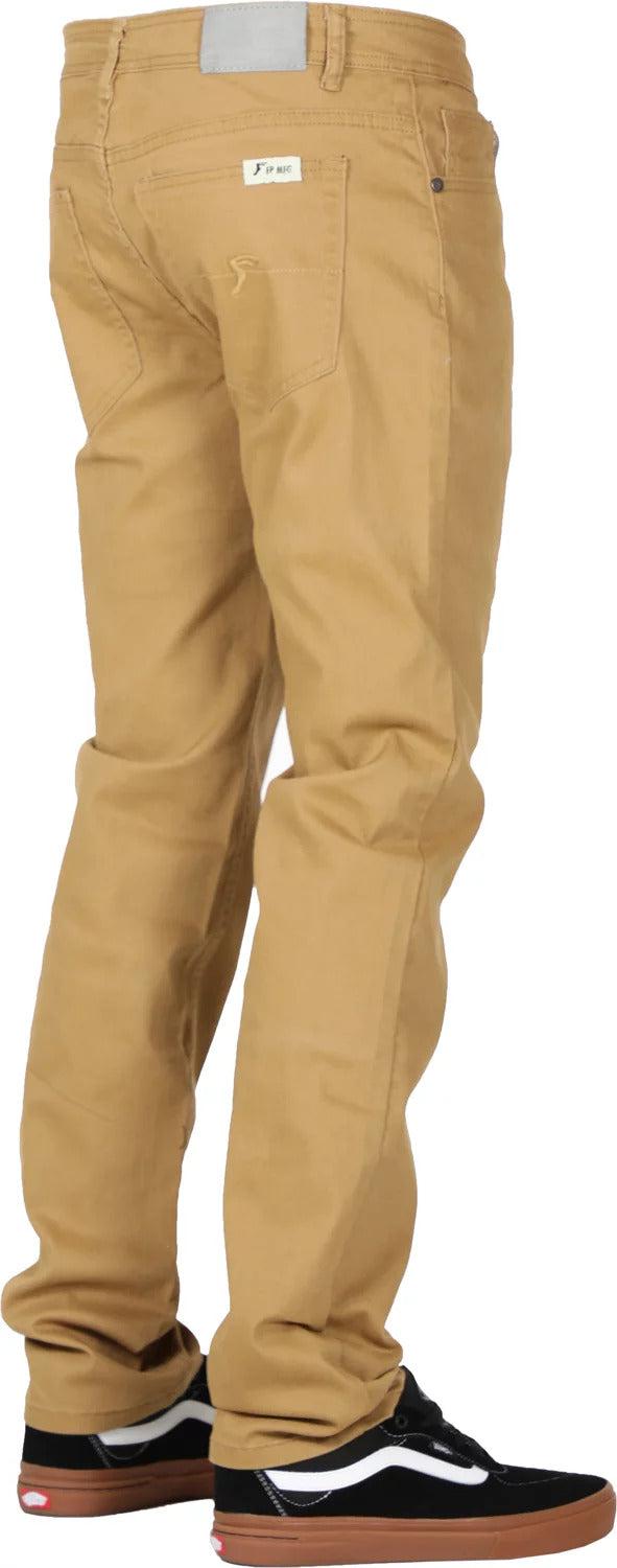 A person is standing, wearing khaki **FP Pants Relaxed Fit Chino Bone** and black sneakers with white accents. The pants, made of stretch fabric, have a small white label near the back pocket. The background is white.