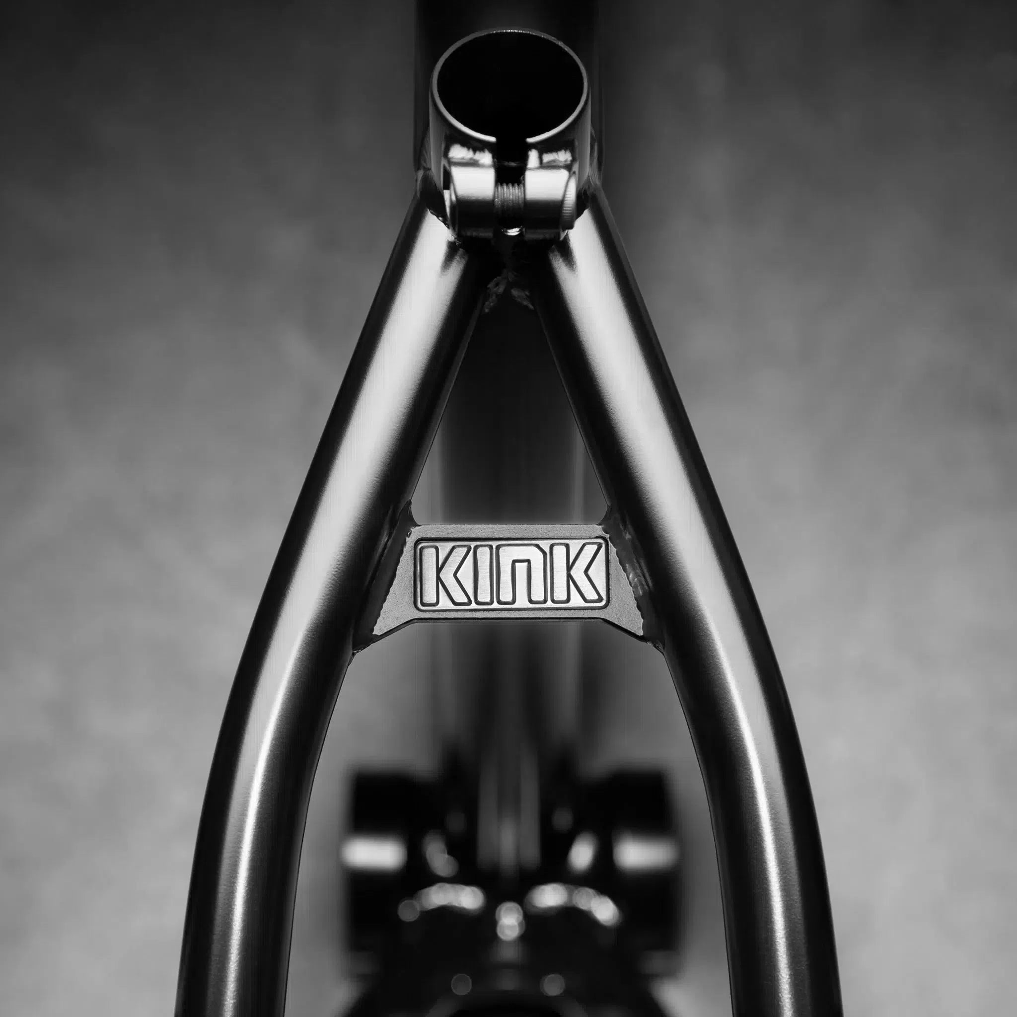 A close-up of the black Kink Royale Frame showcases the brand on a metal plate between the rear tubes. Made from 4130 chromoly tubing, it features integrated chain tensioners for enhanced performance.