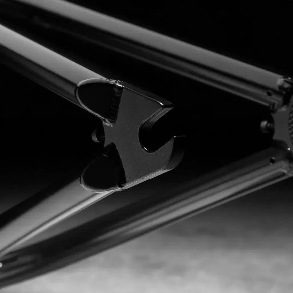 Close-up of a black bicycle frame dropout against a dark background, highlighting the precision craftsmanship synonymous with the Kink Williams (Nathan Williams Signature) Frame.