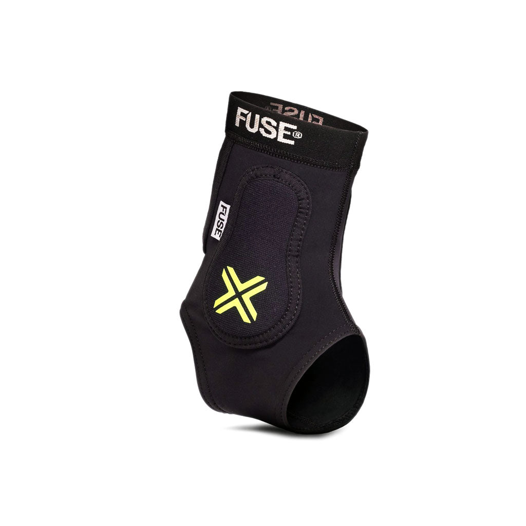 A black Fuse Omega Pro Ankle Guard with yellow X insignia, designed to provide support and stability, featuring EVA foam padding for enhanced comfort.