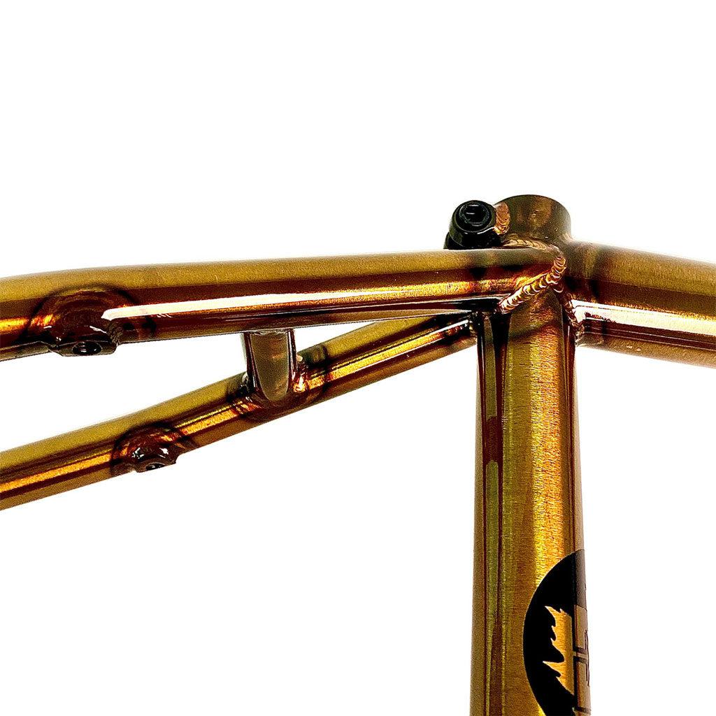 Close-up of a shiny, metallic orange-brown Fit Bike Co Hangman Frame (Jordan Hango Signature USA made), highlighting the seat post area and welding details. This Canadian street beast boasts classic geometry that enhances its sleek, robust design.