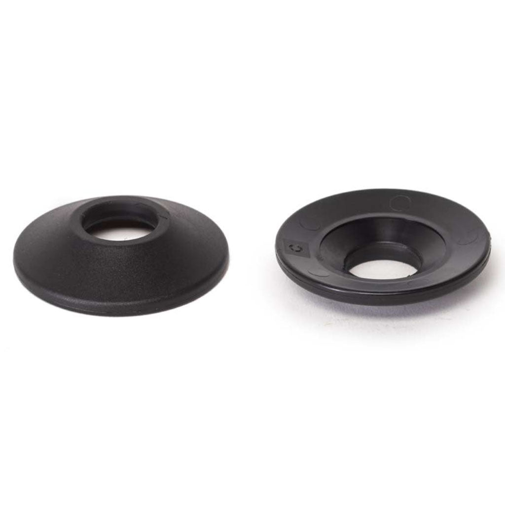 Two black, round plastic Wethepeople Helix Front Hub Guards with central holes rest on a white surface; one lies flat, while the other is slightly raised.