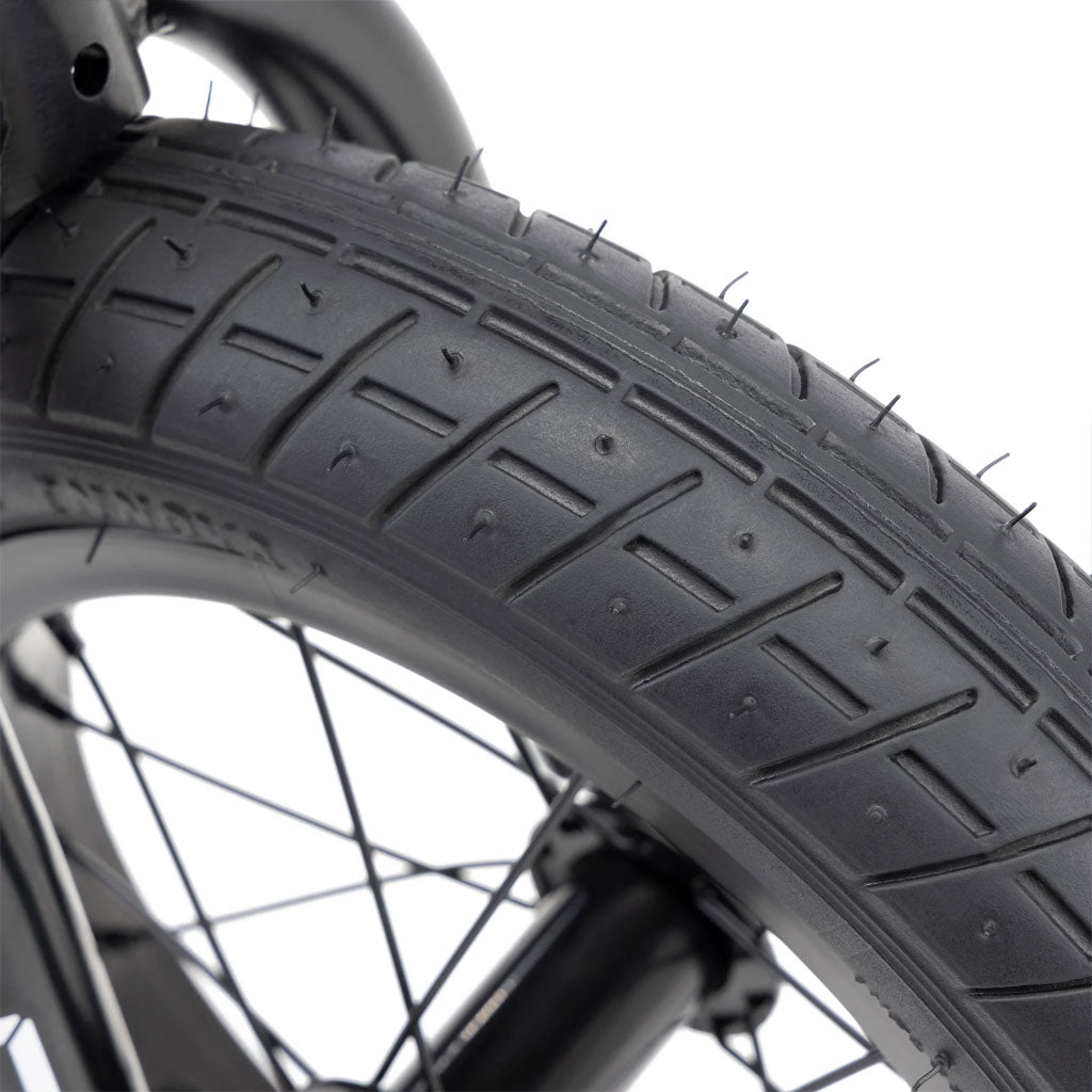 Close-up of a Kink Coast Balance Bike tire, featuring a textured tread pattern and visible spokes, ideal for overcoming challenges.