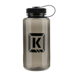 The Kink Refresh Water Bottle is a sleek gray and black BPA-free bottle, featuring a twist-on tethered lid and strap, along with a prominent "K" logo on its side.