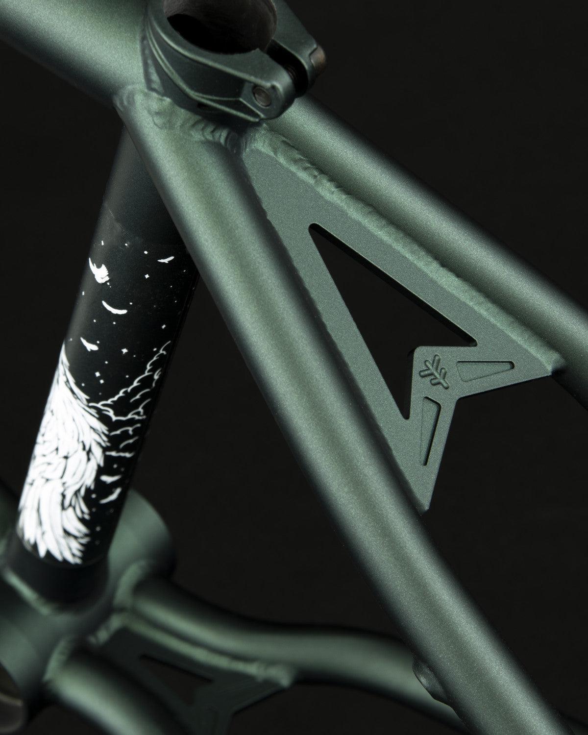 Close-up of the Fly Bikes Aire Frame, a matte green 4130 Cr-Mo bicycle frame featuring a triangular cutout and a sleek black and white design on the vertical tube, showcasing high-quality craftsmanship.