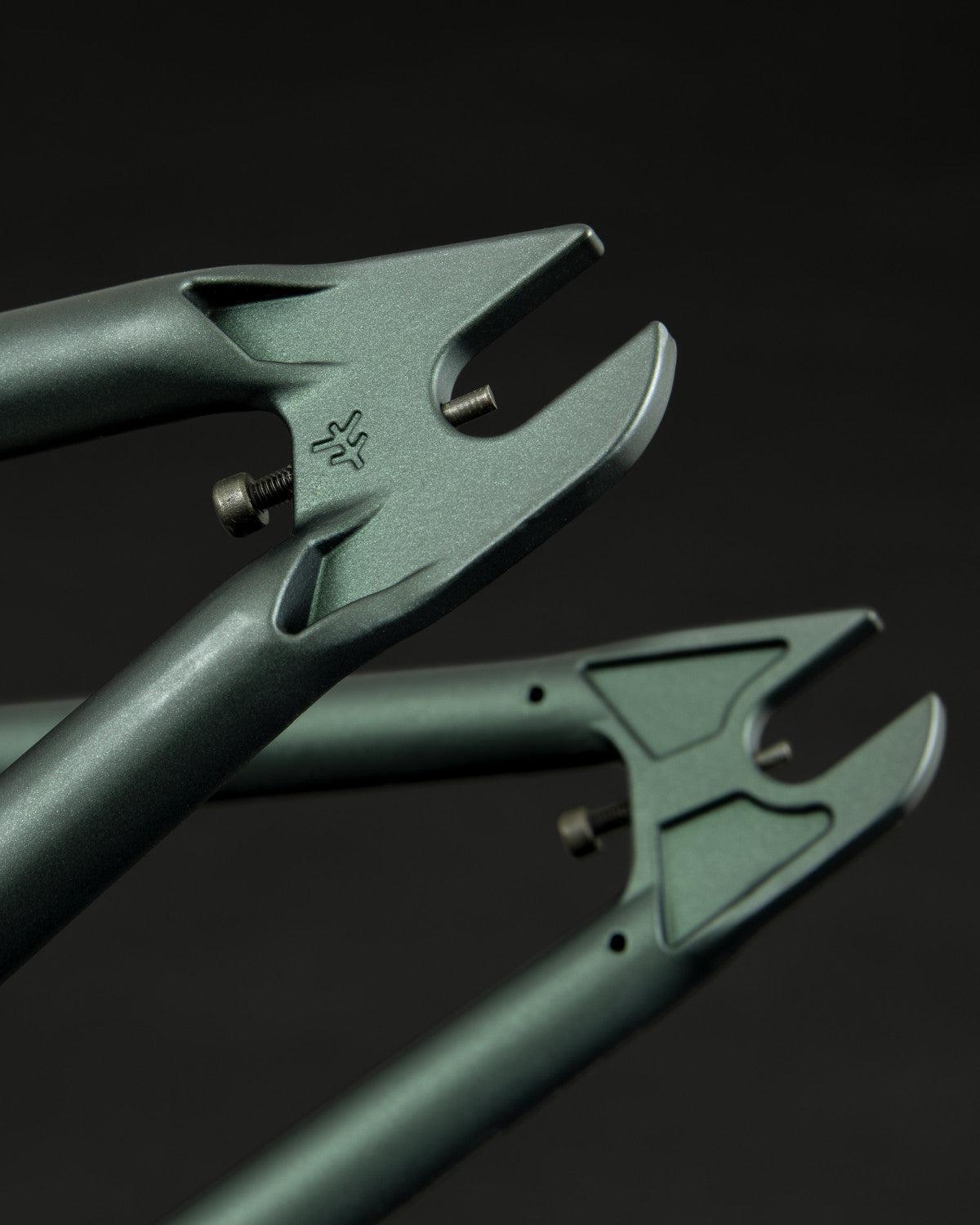 Close-up of a Fly Bikes Aire Frame in metallic green, made from 4130 Cr-Mo steel, featuring investment cast dropouts adorned with a logo.