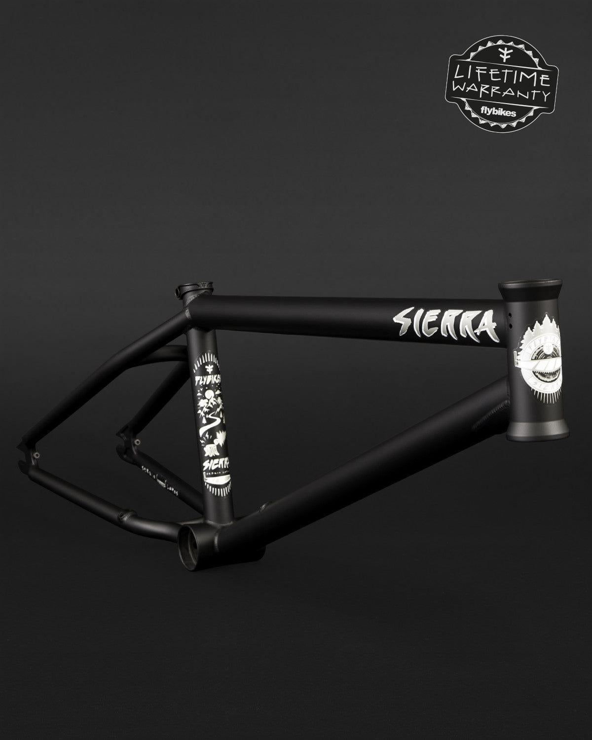 The Fly Bikes Sierra Frame offers durability with its black 4130 CrMo construction, highlighted by sleek white graphics and "SIERRA" text. A "Lifetime Warranty" badge in the top right corner guarantees a trustworthy investment for riders.