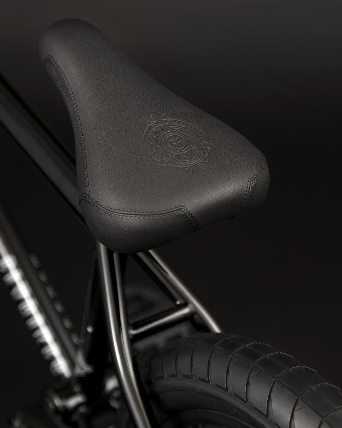 Close-up of the black bicycle seat with stitching and an embossed design, mounted on the CrMo frame of the Fly Bikes Proton CST 20 Inch Bike, perfect for BMX biking enthusiasts.