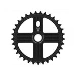 The MCS Neptune Helm Chainwheel in black boasts 25 teeth and features circular cutouts arranged in a cross design, along with the text "Made in USA" on one of its arms.