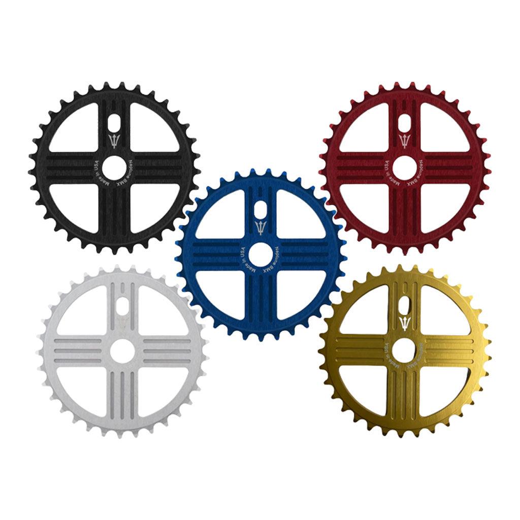 Five MCS Neptune Helm Chainwheels in black, blue, red, silver, and gold colors arranged in a diagonal pattern.