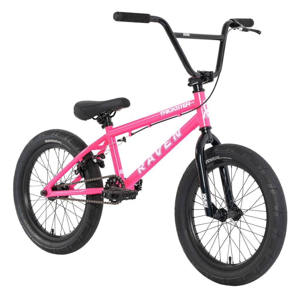 Introducing the Raven Trickster 18 Inch Bike, a pink BMX bicycle adorned with black handlebars and tires. Crafted from hi-tensile steel for enhanced durability, it boasts a robust frame and comes equipped with a comfortable padded black seat. This bike is ideal for beginner riders ready to embark on their adventure.