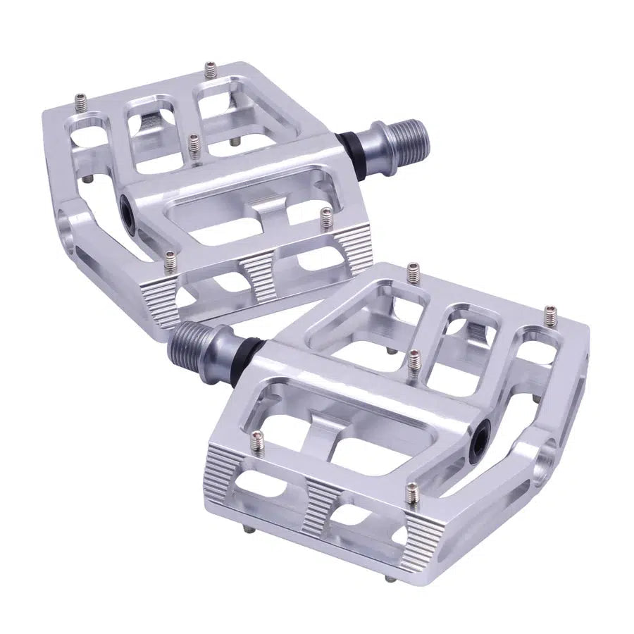 The Snafu Cactus Pro Pedals are a pair of silver metal bicycle pedals featuring a flat platform design with visible axles and a low-profile build. Engineered with precision, these pedals boast CNC-machined components and a robust chromoly MTB spindle for enhanced durability on the trails.