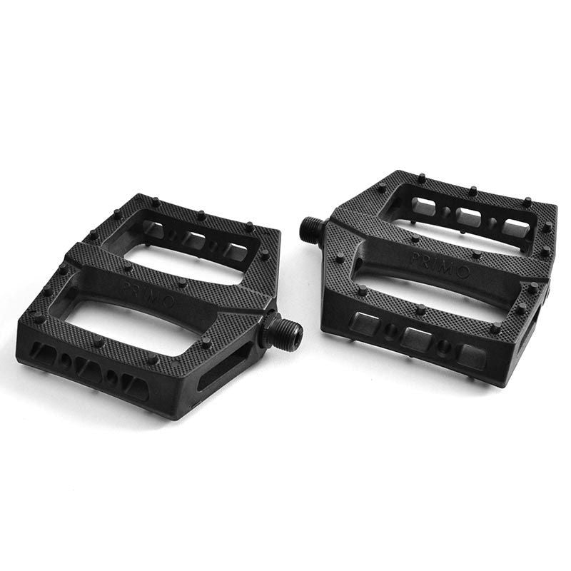 Two black Primo Turbo Pedals with textured surfaces and metal axles are positioned side by side on a plain white background, providing maximum foot placement flexibility.